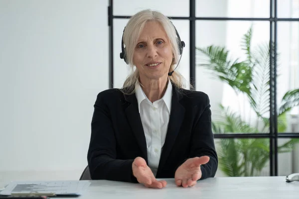 Elderly white-haired woman talks to a camera video call video conference with her business partners — 图库照片