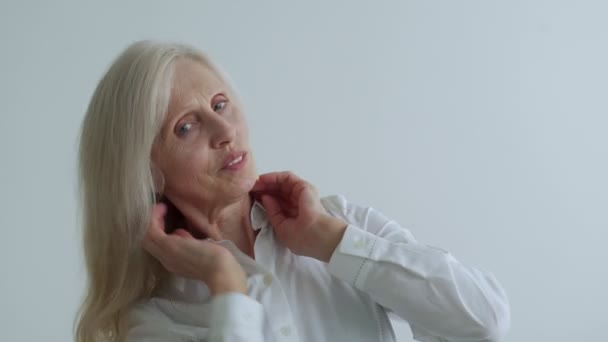 Portrait of a beautiful elderly woman with gray hair straightens her hair — Vídeo de stock