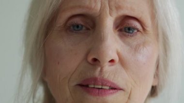 Close-up of the face of an elderly woman with gray hair, looking at the camera
