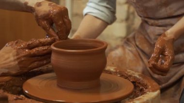 Çömlekçiliğe bir zanaatkarın ellerine rehberlik etmek çömlekçi çarkına çamur atmayı öğretmek. Öğretmen ve öğrenci konsepti