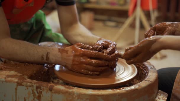 Aardewerk training, een close-up van een man pottenbakker leert een man hoe een kom bruine klei goed te vormen op een pottenbakker — Stockvideo