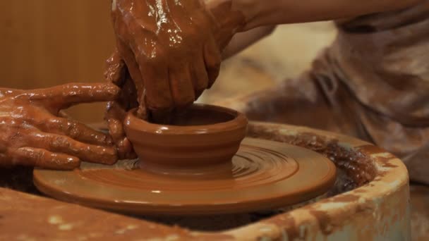 Handen van de ervaren meester Pottenbakker en vrouw handen, opleiding van de vrouw om de productie van aardewerk op een pottenbakkerswiel — Stockvideo