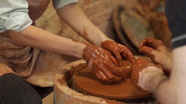 Training voor het werk in het pottenbakkerswiel. Een man en een vrouw werken samen met klei. — Stockvideo
