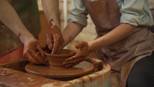 Aardewerk training, een close-up van een man pottenbakker leert een man hoe een kom bruine klei goed te vormen op een pottenbakker — Stockvideo