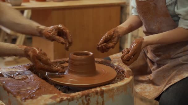 Aardewerk training, een close-up van een man pottenbakker leert een man hoe een kom bruine klei goed te vormen op een pottenbakker — Stockvideo