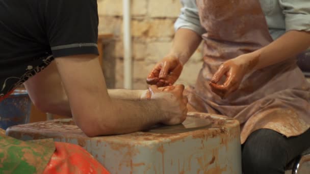 Muž hrnčíř, který učí umění dělat hrnce pro ženu. Žena pracující na hrnčířském kole — Stock video