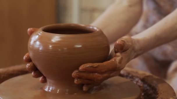 Oudere handen van een pottenbakker, die een aarden pot op de cirkel maakt. Oude vrouw maakt handgemaakte keramiek van klei — Stockvideo