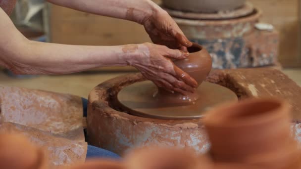 Manos mayores de un alfarero, creando un frasco de tierra en el círculo. Mujer vieja hace cerámica hecha a mano de arcilla — Vídeo de stock