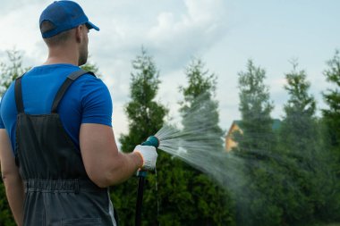 Bahçıvanlık ve bakım. Çimleri sulayan hortumla insan ellerine yakın durun.