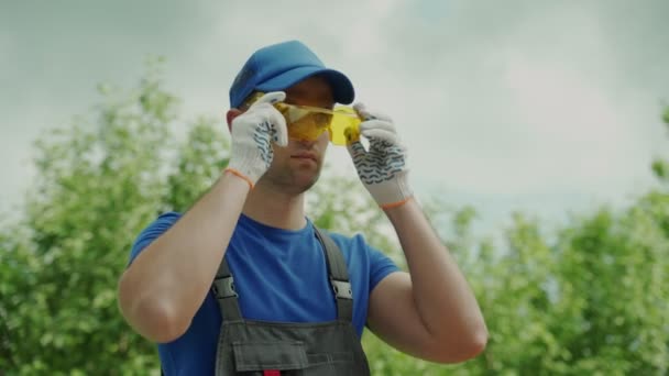 Προσωπογραφία άνδρα εργαζομένου με κίτρινα γυαλιά και γάντια ασφαλείας — Αρχείο Βίντεο