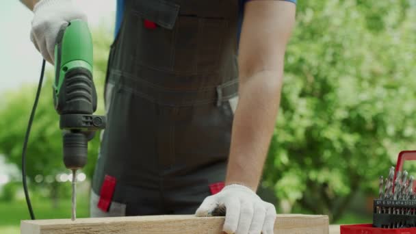Gros plan main de charpentier perce bois un trou avec une perceuse électrique — Video