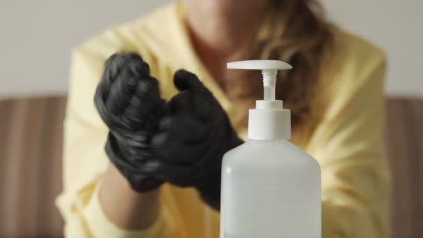 Mulher mãos em luvas pretas limpeza mãos com desinfetante em garrafa, close-up — Vídeo de Stock