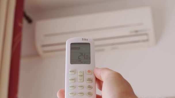 Gros plan de la main de l'homme est allumé climatiseur type split par télécommande. — Video