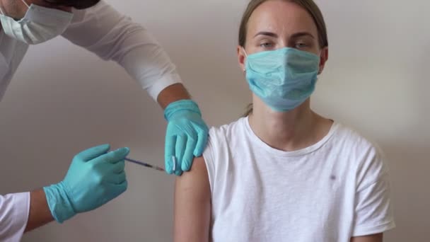 La mujer y su médico usando máscaras faciales y recibiendo una vacuna en un consultorio médico. Médico inyectando a una paciente femenina en la clínica — Vídeos de Stock
