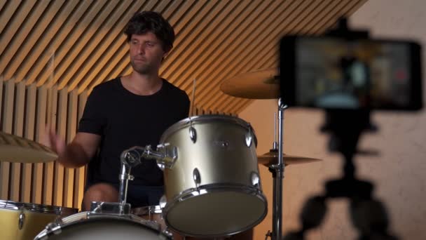 Drummer man plays online and records video on smartphone. A male drummer conducts online training — Stock video
