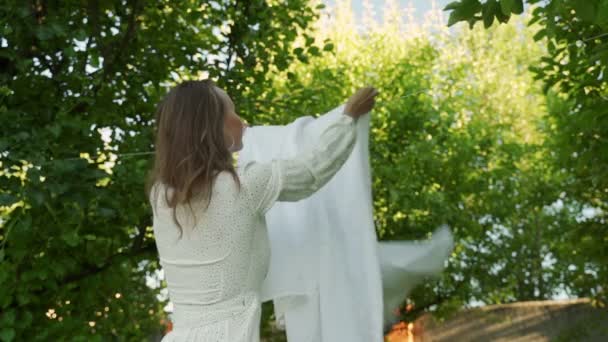 Temiz havadaki çamaşır ipine temiz çarşaf asan genç bir kadının ağır çekimde — Stok video