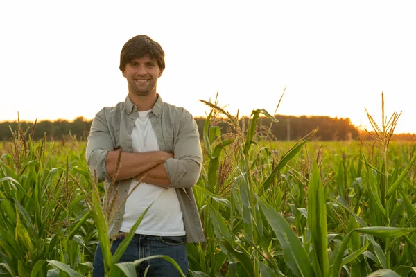 Ritratto di un contadino con le braccia incrociate, in piedi in un campo di grano, guardando la telecamera — Foto Stock