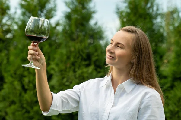 Jonge vrouw drinkt rode wijn in een wijngaard op een zonnige dag — Stockfoto