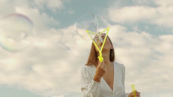 Giovane donna che soffia bolle di sapone su sfondo cielo blu, divertirsi all'aperto nella giornata di sole — Video Stock