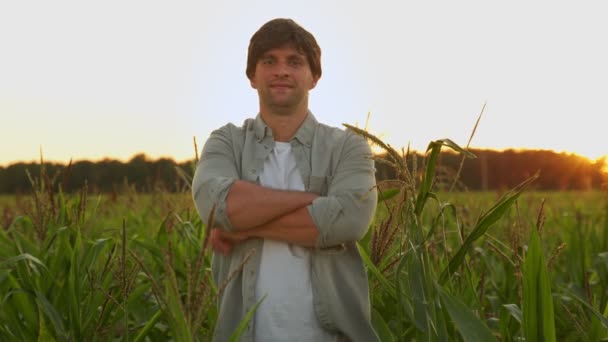 Портрет фермера со скрещенными руками, стоящего на кукурузном поле, смотрящего в камеру — стоковое видео