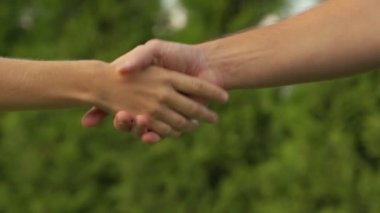 Bahçede el sıkışan iki kişi.