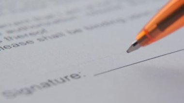 Odaklanmış genç bir iş adamının yakın çekimi imzasını bir kağıda koyar..