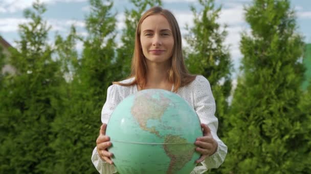 Die junge Frau hält eine Weltkugel in den Händen und reicht sie in die Kamera. Das Konzept der Ökologie und der Rettung des Planeten — Stockvideo