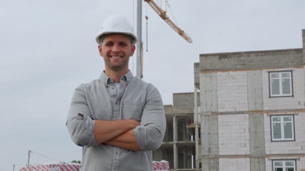 Portret pięknego inżyniera z skrzyżowanymi ramionami i uśmiechem na tle budowanego domu — Wideo stockowe