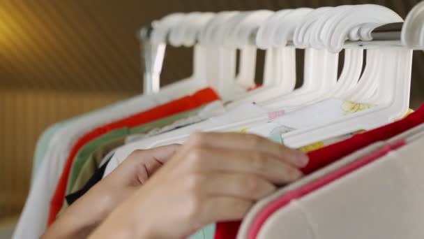 Gros plan d'une main de femme choisissant des vêtements et des T-shirts à prix réduit dans un magasin, une recherche ou un achat — Video