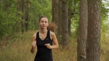 Güzel bir kadın parkın etrafında koşuyor. Atletik genç ve güzel bir kadın ormanda koşuyor..