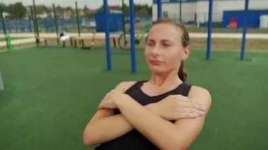 Formda bir kadın, açık havada tahta tahtalarda yatarken karın kaslarını çalıştırır.