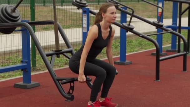 Młoda fitness kobieta robi ciężką martwą windę w symulatorze na boisku sportowym na świeżym powietrzu — Wideo stockowe