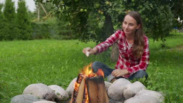 Kobieta je pianki podczas kempingu przy ognisku — Wideo stockowe