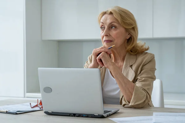 Una mujer de negocios de edad avanzada inspirada considerando nuevas ideas creativas en el lugar de trabajo. — Foto de Stock