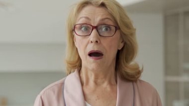 Tarz sahibi, yaşlı, şaşkın, ağzı açık dışarı bakan bir kadın.