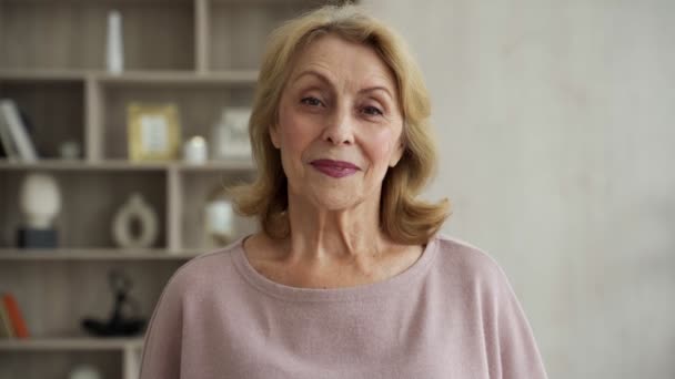 Sorrindo maduro de cabelos grisalhos mulher de meia-idade olhando para a câmera, senhora idosa feliz posando em casa dentro de casa — Vídeo de Stock
