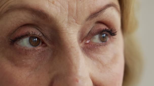 離れて見ている高齢者の女性の悲しい茶色の目を、クローズアップ撮影 — ストック動画