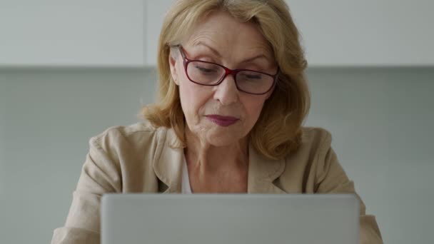 Una anciana sonriente usando un portátil y mirando a la cámara. Una mujer de negocios usa su portátil. — Vídeo de stock