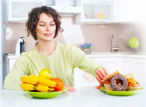 Woman choosing between fruits and sweets Royalty Free Stock Photos