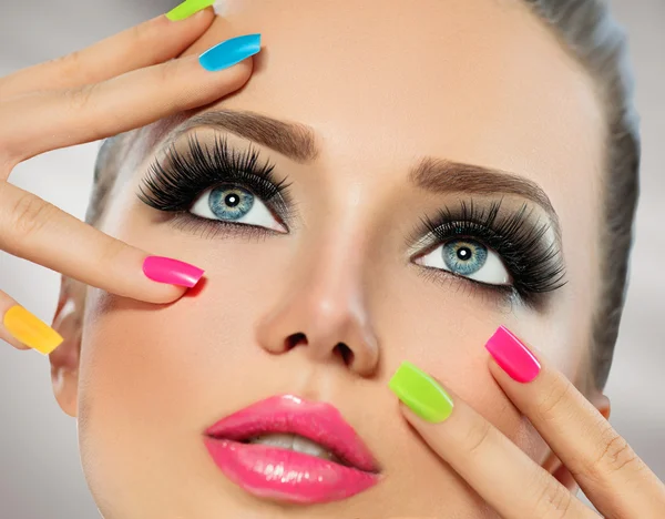 Meisje gezicht met kleurrijke nagellak. — Stockfoto