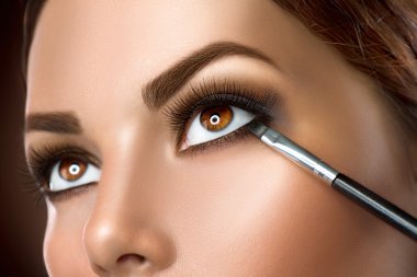 Woman applying makeup closeup. clipart