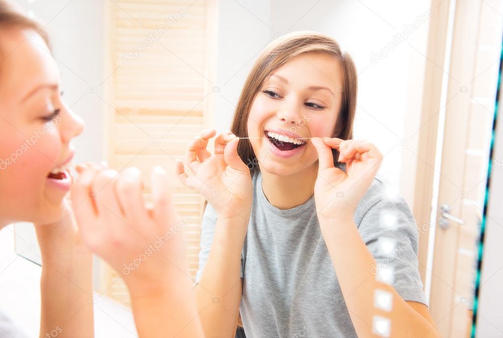 Teenage girl flossing her teeth