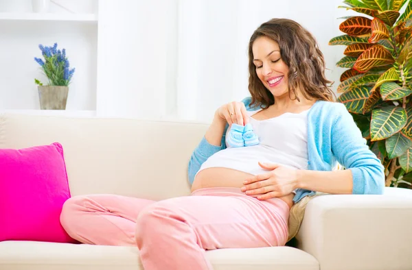 Femme enceinte tenant des chaussures de bébé — Photo