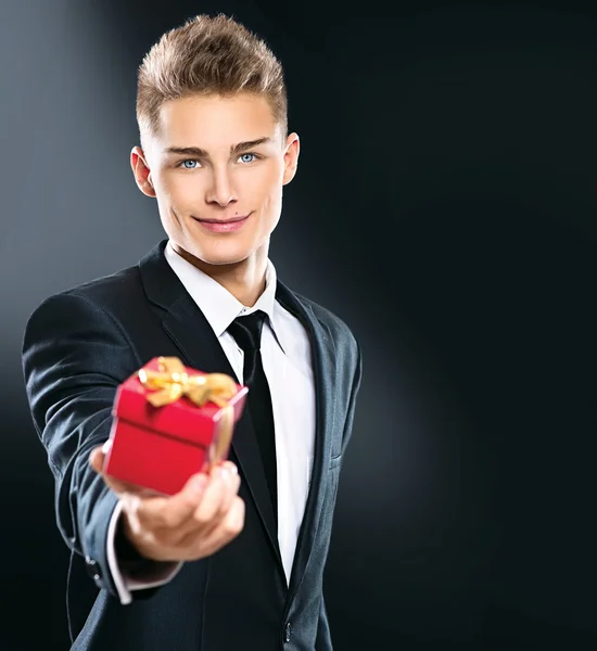 Young man giving red gift box — Stock Photo, Image