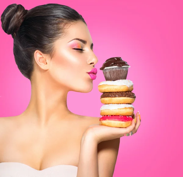 Mädchen nimmt Süßigkeiten und bunte Donuts — Stockfoto