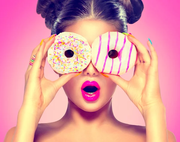 Modelo menina tomando donuts coloridos . — Fotografia de Stock