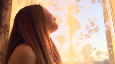 Kız perdeleri büyük pencerede açar