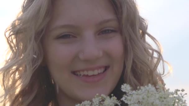 Menina cheirando flores selvagens — Vídeo de Stock