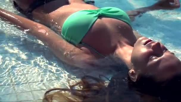 Mujer joven acostada en la piscina — Vídeo de stock