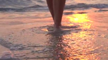 Üzerinde çıplak ayakla günbatımı üzerinde yürüyen kadın